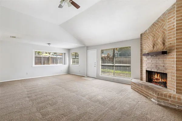 a view of an empty room with a fireplace and a window