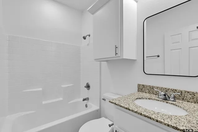 a bathroom with a granite countertop sink mirror vanity and bathtub