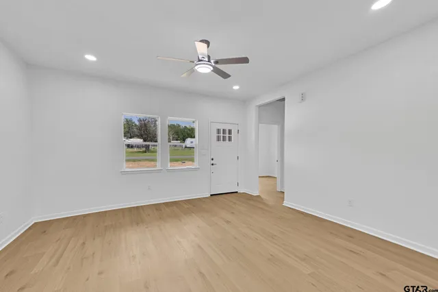 an empty room with a window and ceiling fan