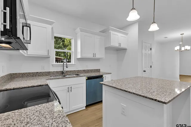 a kitchen with granite countertop kitchen island a sink appliances and a counter space