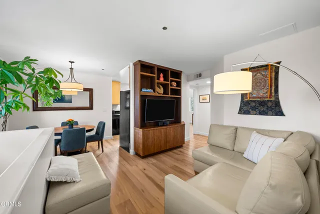 a kitchen with stainless steel appliances granite countertop a stove a refrigerator a sink a dining table and chairs with wooden floor