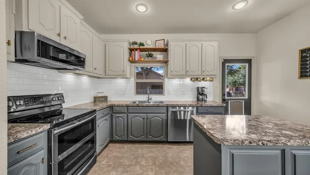 a kitchen with stainless steel appliances granite countertop a stove microwave and sink