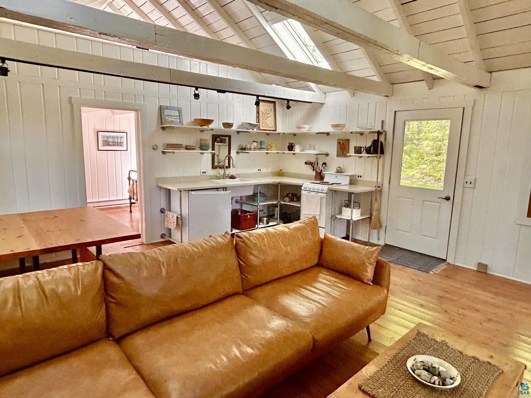 1596 North Shore Road La Pointe, WI 54850 - Photo 2 of 21 Vaulted wood-finish ceiling with exposed beams, wood-finish flooring, white panel walls, open shelving, and a glass-paneled exterior door