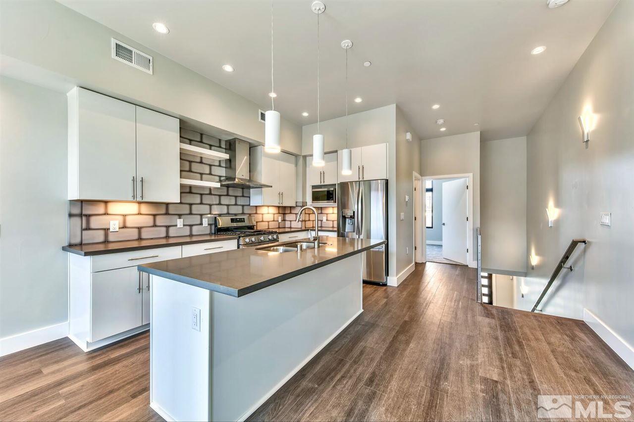 504 Mill Street Reno, NV 89502 - Photo 3 of 22 a kitchen with stainless steel appliances kitchen island granite countertop a stove top oven a sink a refrigerator and white cabinets with wooden floor