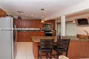 a kitchen with granite countertop a refrigerator stove microwave and cabinets