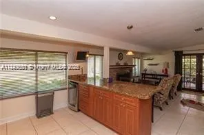a kitchen with kitchen island granite countertop a stove top oven a sink a dining table and chairs