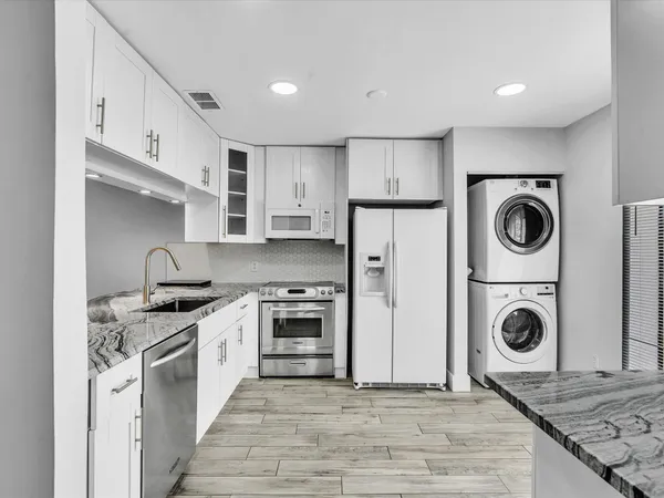 a kitchen with stainless steel appliances granite countertop a stove a refrigerator and a sink