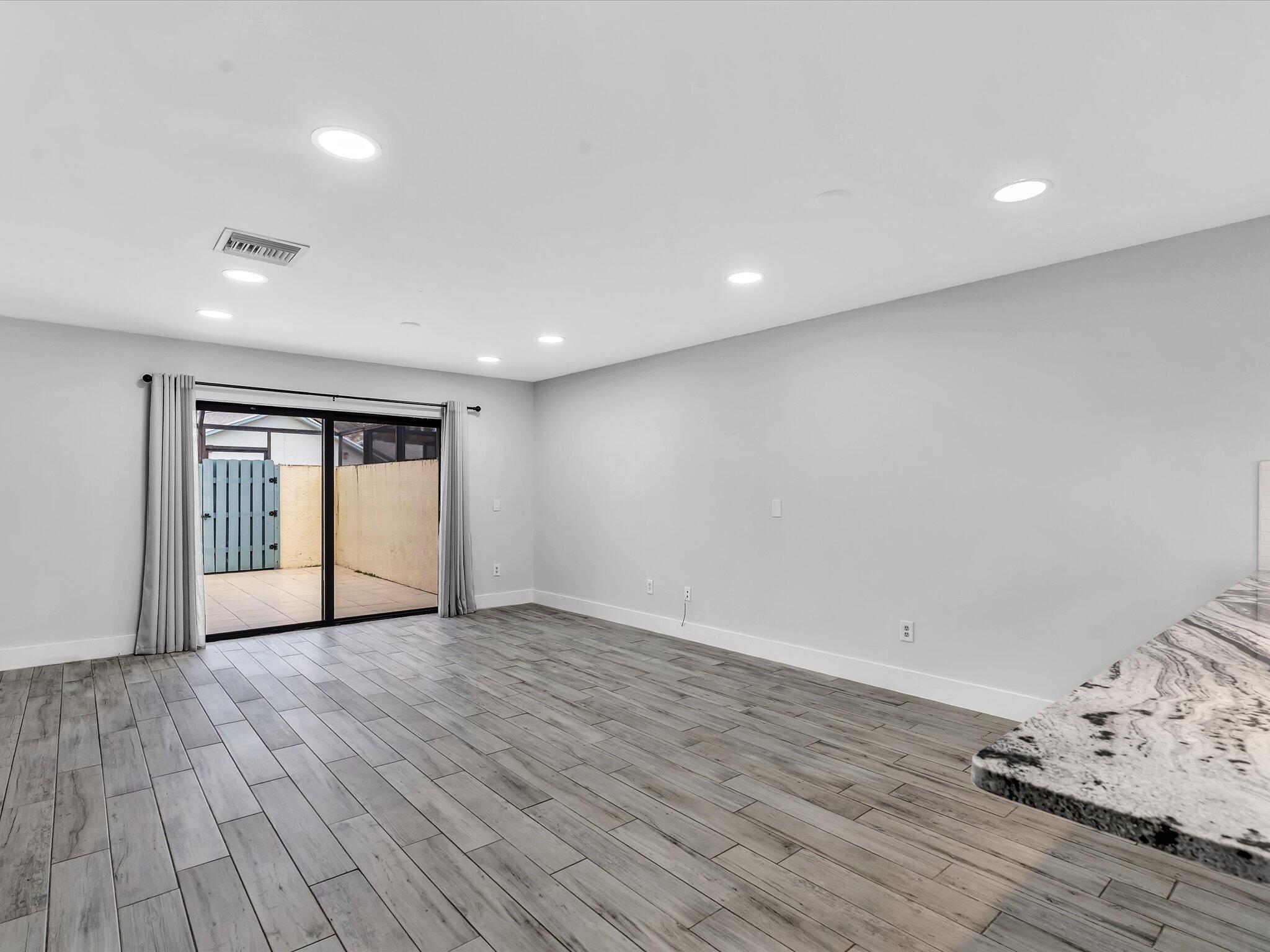 9095 Southwest 21st Court, Unit D Boca Raton, FL 33428 - Photo 5 of 36 a view of an empty room with wooden floor and a window