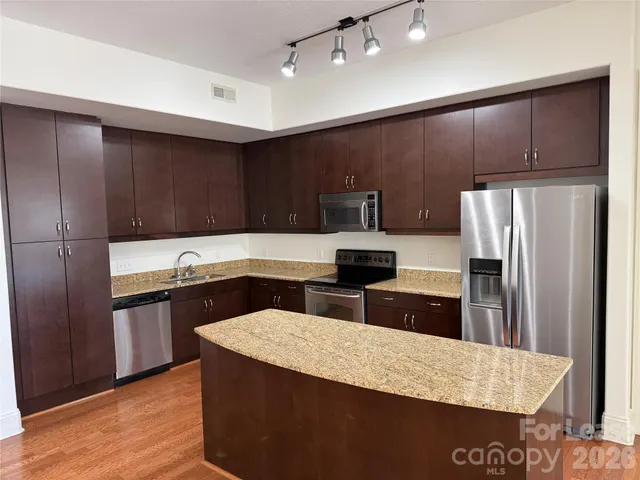a kitchen with stainless steel appliances wooden cabinets and wooden floor