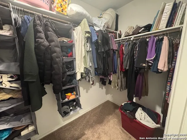 a view of walk in closet with clothes and shoes