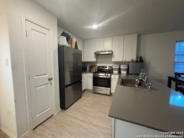 a kitchen with a refrigerator a stove and a sink