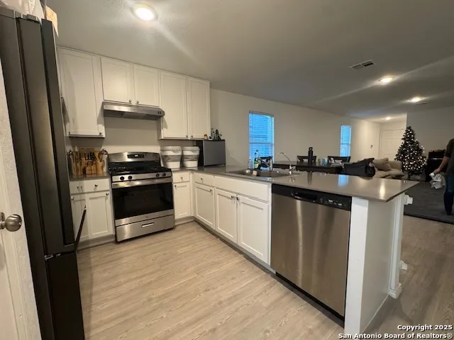 a kitchen with stainless steel appliances a sink stove refrigerator and cabinets
