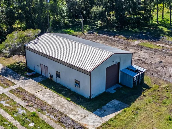 an aerial view of residential house with outdoor space and trees all around