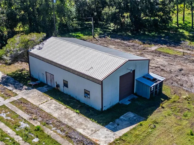 an aerial view of residential house with outdoor space and trees all around
