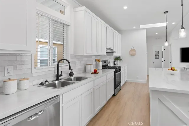 a kitchen with kitchen island a sink appliances cabinets and a counter top space