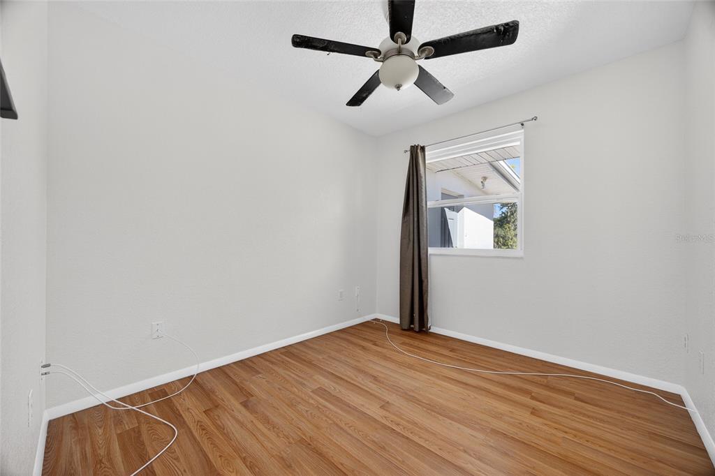 2136 Barksdale Street Port Charlotte, FL 33948 - Photo 18 of 33 an empty room with wooden floor ceiling fan and windows