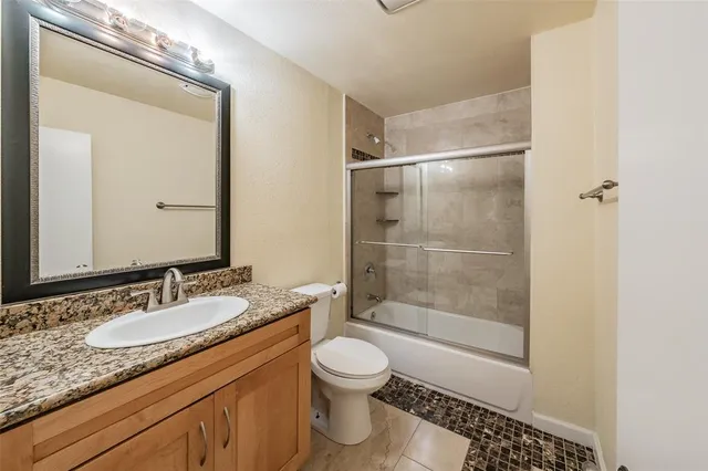a bathroom with a granite countertop sink a toilet and shower