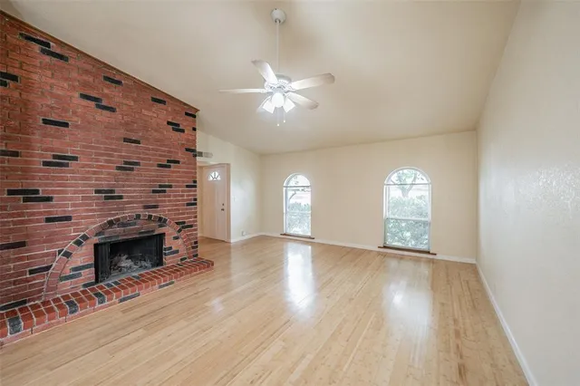 an empty room with windows and fireplace