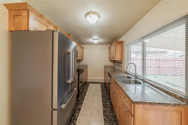 a kitchen with granite countertop a sink a counter top space and stainless steel appliances