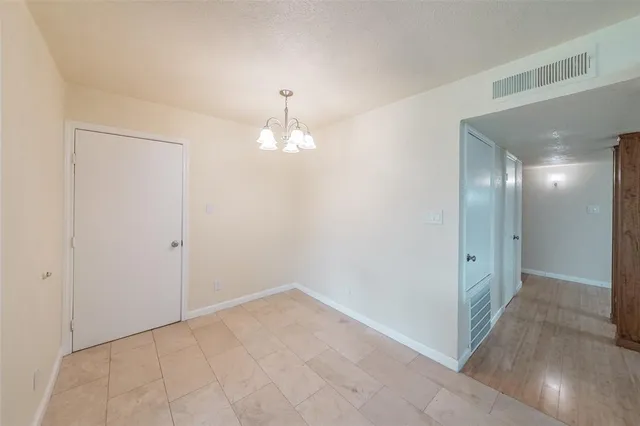 an empty room with kitchen view and wooden floor