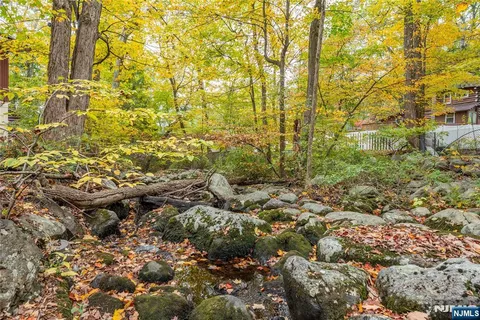 a view of residential house with green space and tree in the background