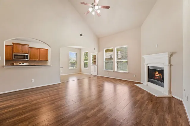 a view of an empty room with wooden floor and a fireplace