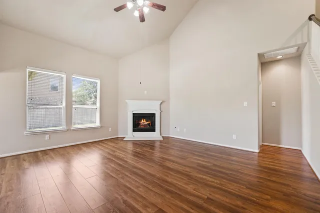 a view of an empty room with wooden floor fireplace and a window