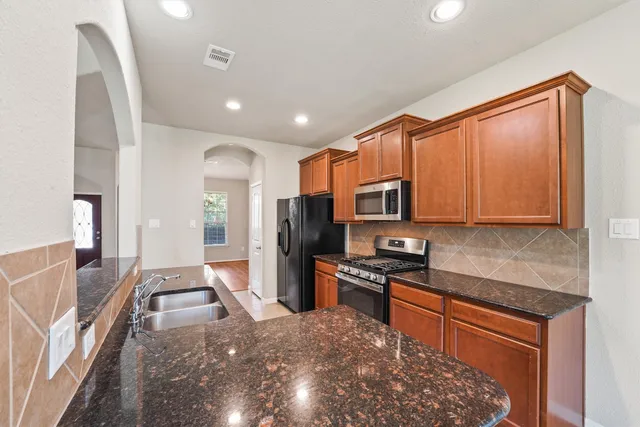 a kitchen with stainless steel appliances granite countertop a refrigerator a stove top oven a sink and dishwasher