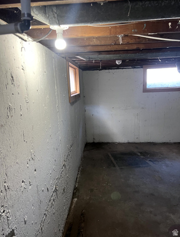 3161 Adams Avenue Ogden, UT 84403 - Photo 13 of 17 Unfinished basement space featuring exposed ceiling joists, concrete walls, two windows with wood trim, and a concrete floor
