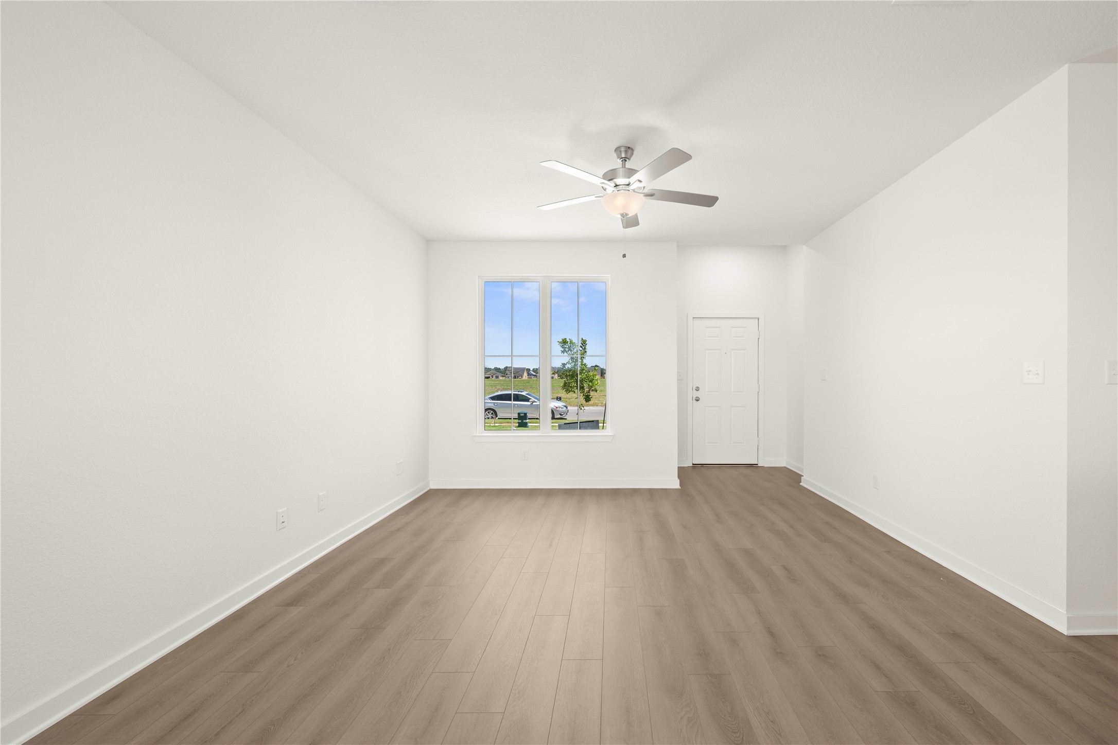 228 Gus Loop Georgetown, TX 78626 - Photo 12 of 19 A versatile living area features durable wood flooring and a modern ceiling fan, with ample natural light from a large window.