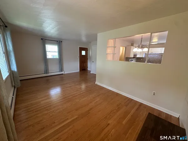 a view of an empty room with wooden floor and a window