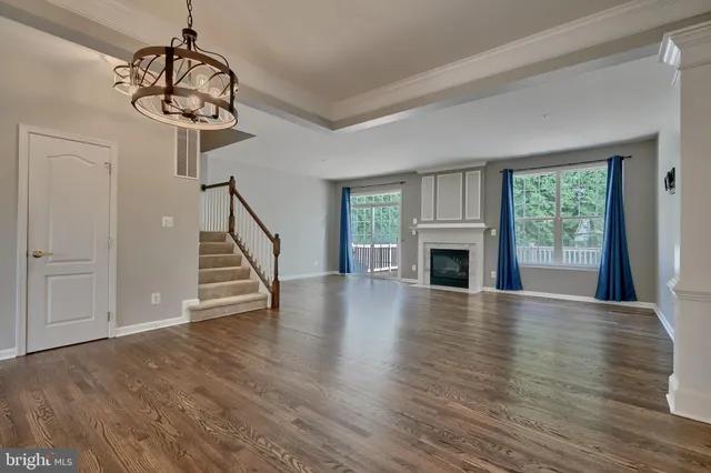 a view of an empty room with wooden floor fireplace and a window