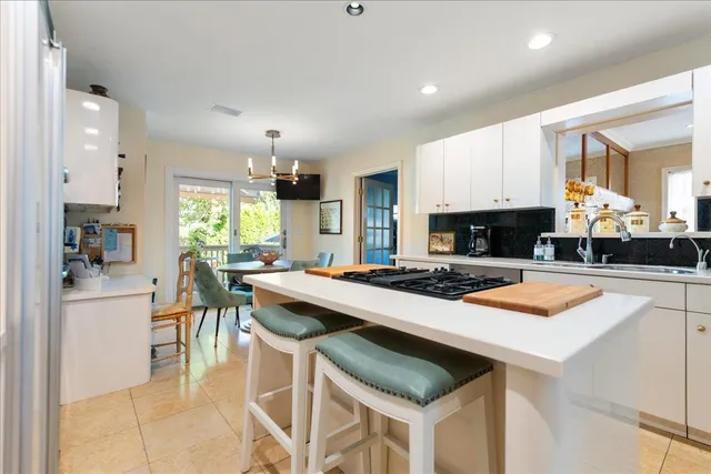 a kitchen with stainless steel appliances granite countertop a stove a sink a refrigerator a dining table and chairs