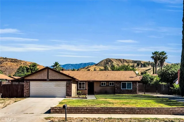 a view of a white house with a big yard and large trees