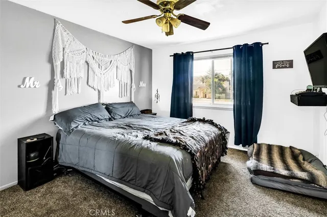 a bedroom with a bed and a flat tv screen on dresser