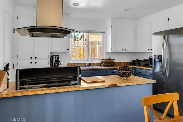 a kitchen with stainless steel appliances a stove a refrigerator a sink and white cabinets