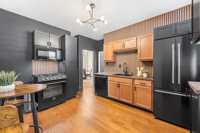 a kitchen with stainless steel appliances granite countertop a refrigerator a stove a sink dishwasher a dining table and chairs with wooden floor