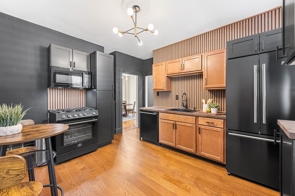 8 Spring Garden Street, Unit 3 Boston, MA 02125 - Photo 1 of 37 a kitchen with stainless steel appliances granite countertop a refrigerator a stove a sink dishwasher a dining table and chairs with wooden floor