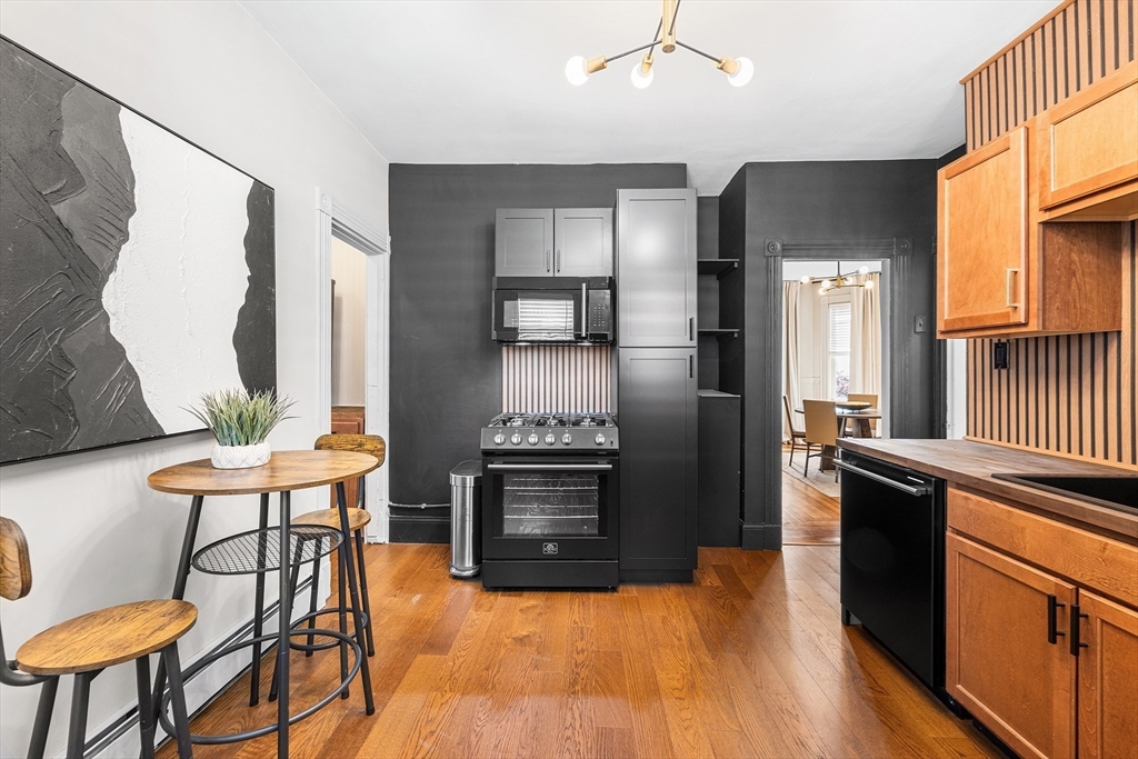8 Spring Garden Street, Unit 3 Boston, MA 02125 - Photo 14 of 37 a kitchen with stainless steel appliances kitchen island granite countertop a stove a refrigerator and a dining table with wooden floor