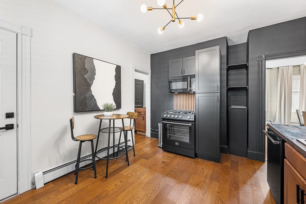 8 Spring Garden Street, Unit 3 Boston, MA 02125 - Photo 15 of 37 a kitchen with stainless steel appliances granite countertop a refrigerator a stove a sink and a dining table with white countertops