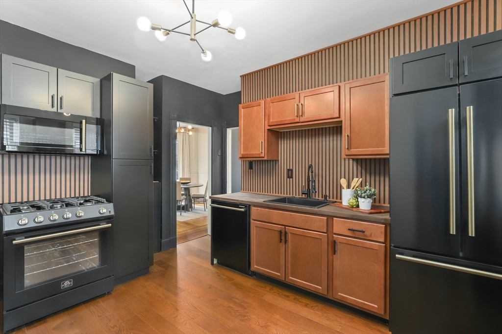 8 Spring Garden Street, Unit 3 Boston, MA 02125 - Photo 17 of 37 a kitchen with stainless steel appliances granite countertop a refrigerator a sink dishwasher a stove and white countertops with wooden floor