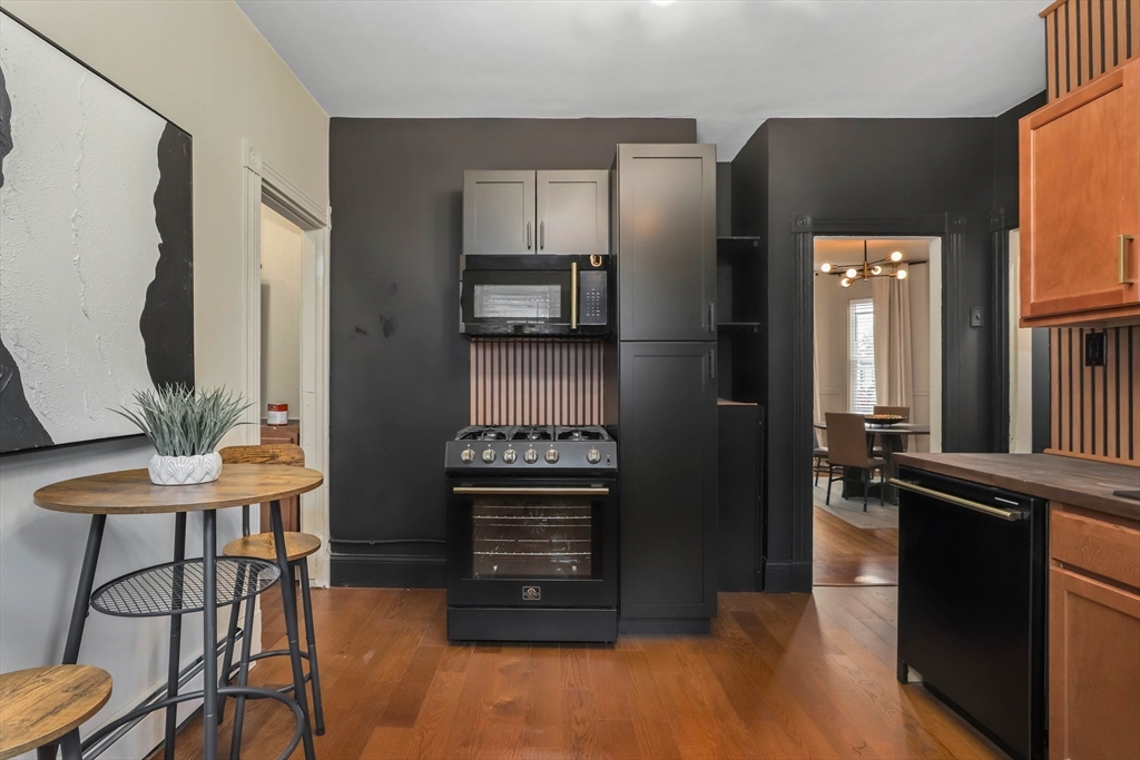 8 Spring Garden Street, Unit 3 Boston, MA 02125 - Photo 18 of 37 a kitchen with stainless steel appliances kitchen island granite countertop a refrigerator a stove and a stove with wooden floor
