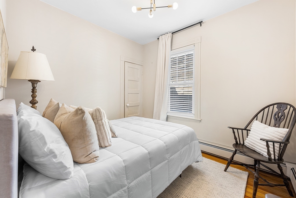8 Spring Garden Street, Unit 3 Boston, MA 02125 - Photo 24 of 37 a bedroom with a bed a chair and a lamp on the dresser
