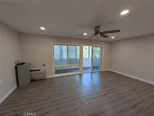 a view of an empty room with a window and wooden floor