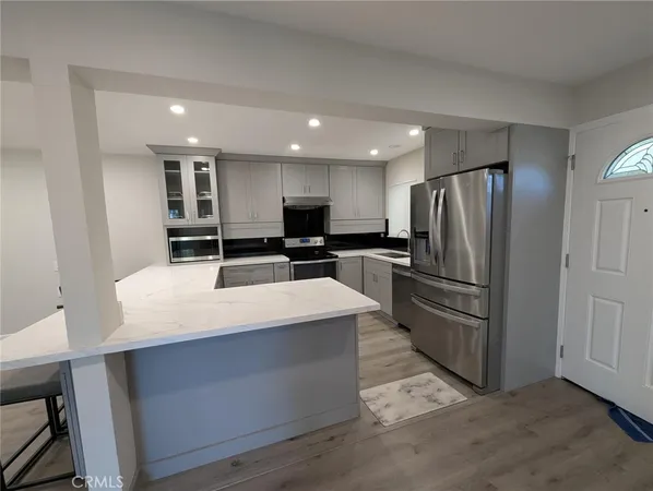 a large kitchen with stainless steel appliances a refrigerator and a stove top oven