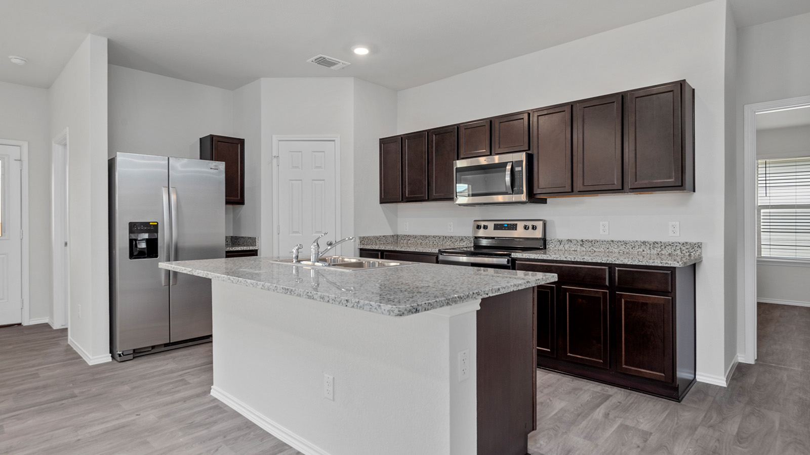 1417 Victory Rnch Trail Killeen, TX 76549 - Photo 5 of 22 A contemporary kitchen showcasing dark wood cabinetry, stainless steel appliances, and a central island with a double sink.