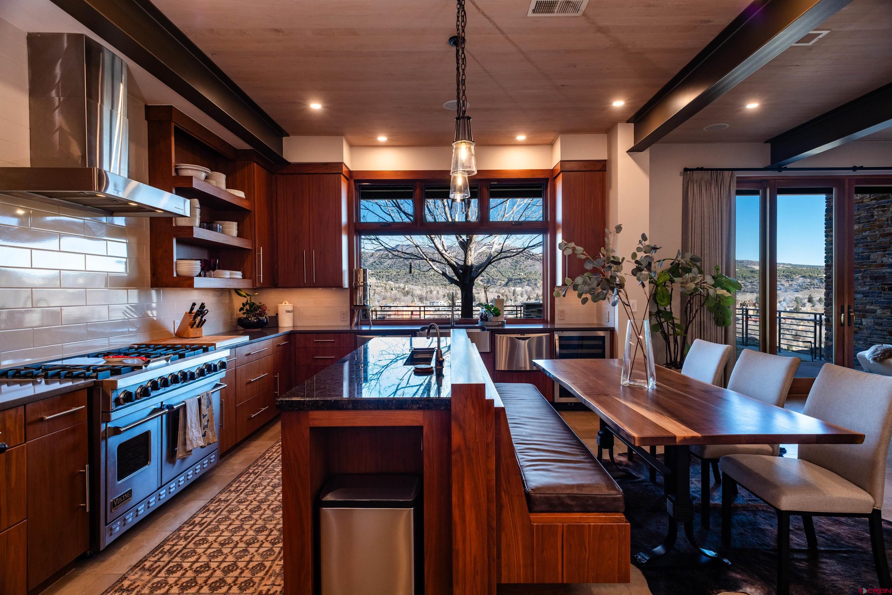 a kitchen with stainless steel appliances granite countertop a stove top oven a dining table and chairs with wooden floor