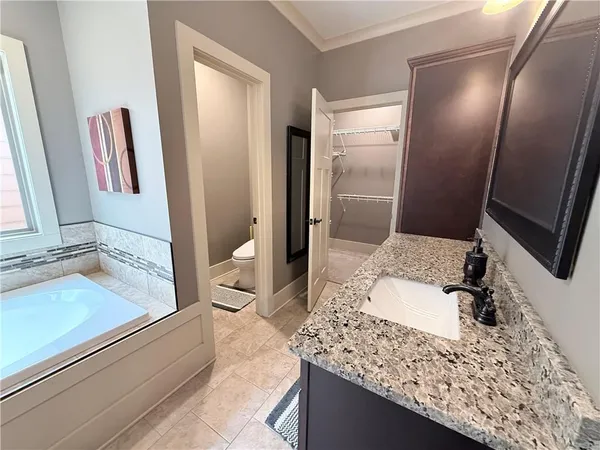 a bathroom with a granite countertop toilet sink and mirror