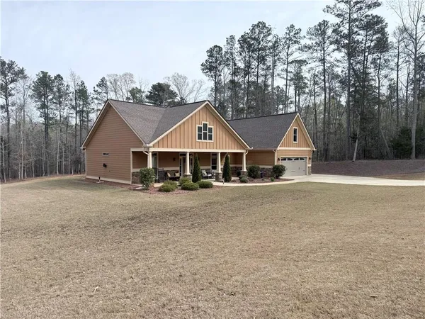 a view of a house with a yard and large trees
