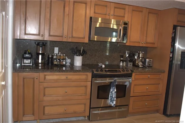 a kitchen with granite countertop white cabinets and stainless steel appliances